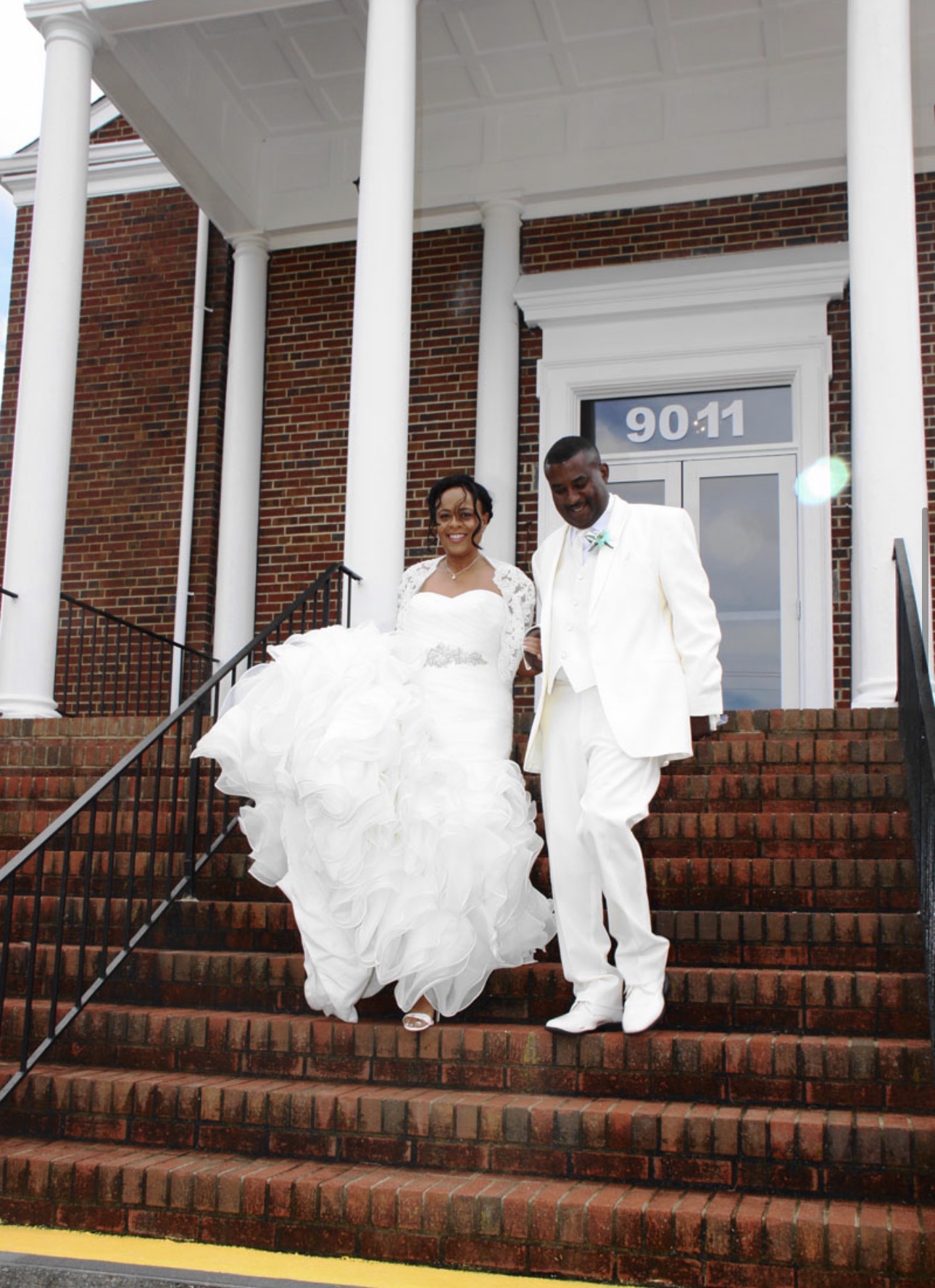 Newlywed couple in ivory walking down the brick church steps together